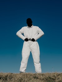 a man in a white suit standing in a field
